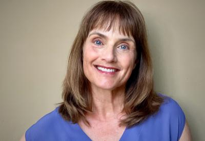A picture of Dr. Leslie Ellis - smiling, wearing a bright blue shirt.