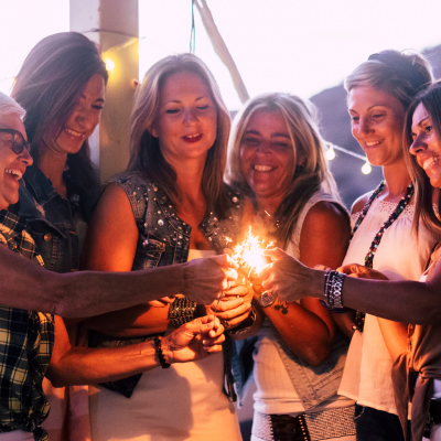 group of midlife women smiling together & holding sparkler