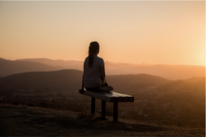 Woman sitting on a bench looking at the sunrise