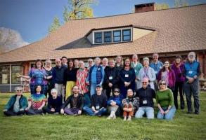Group of Focusers posing together on grass in front of a cabin.